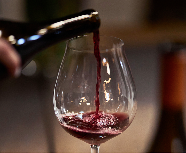 Red wine being poured into a glass with a blurred background