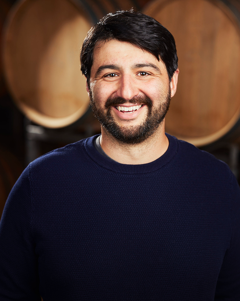 Brandon Hasart Vineyard Manager headshot in front of wine barrels