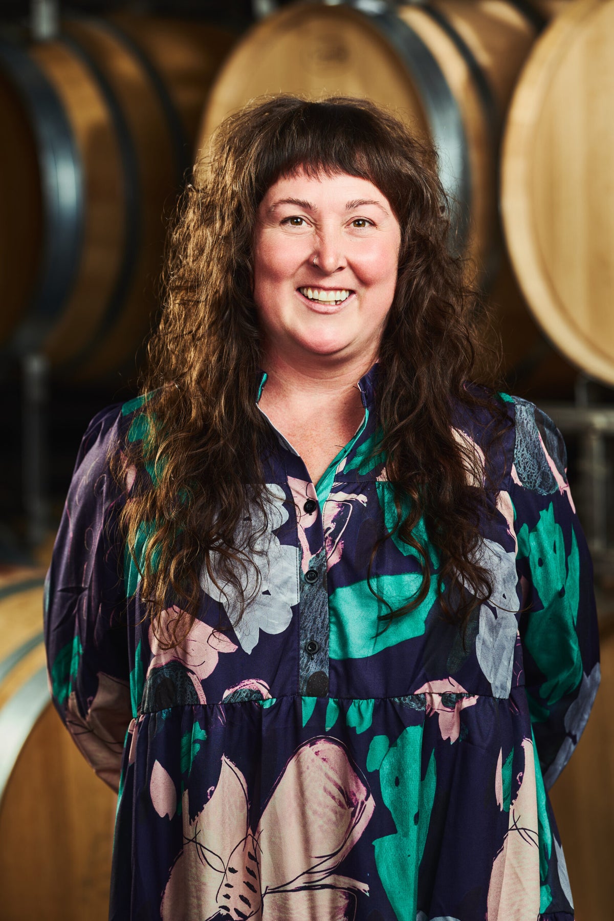 Bri Bova Senior Manager, Hospitality headshot in front of wine barrels