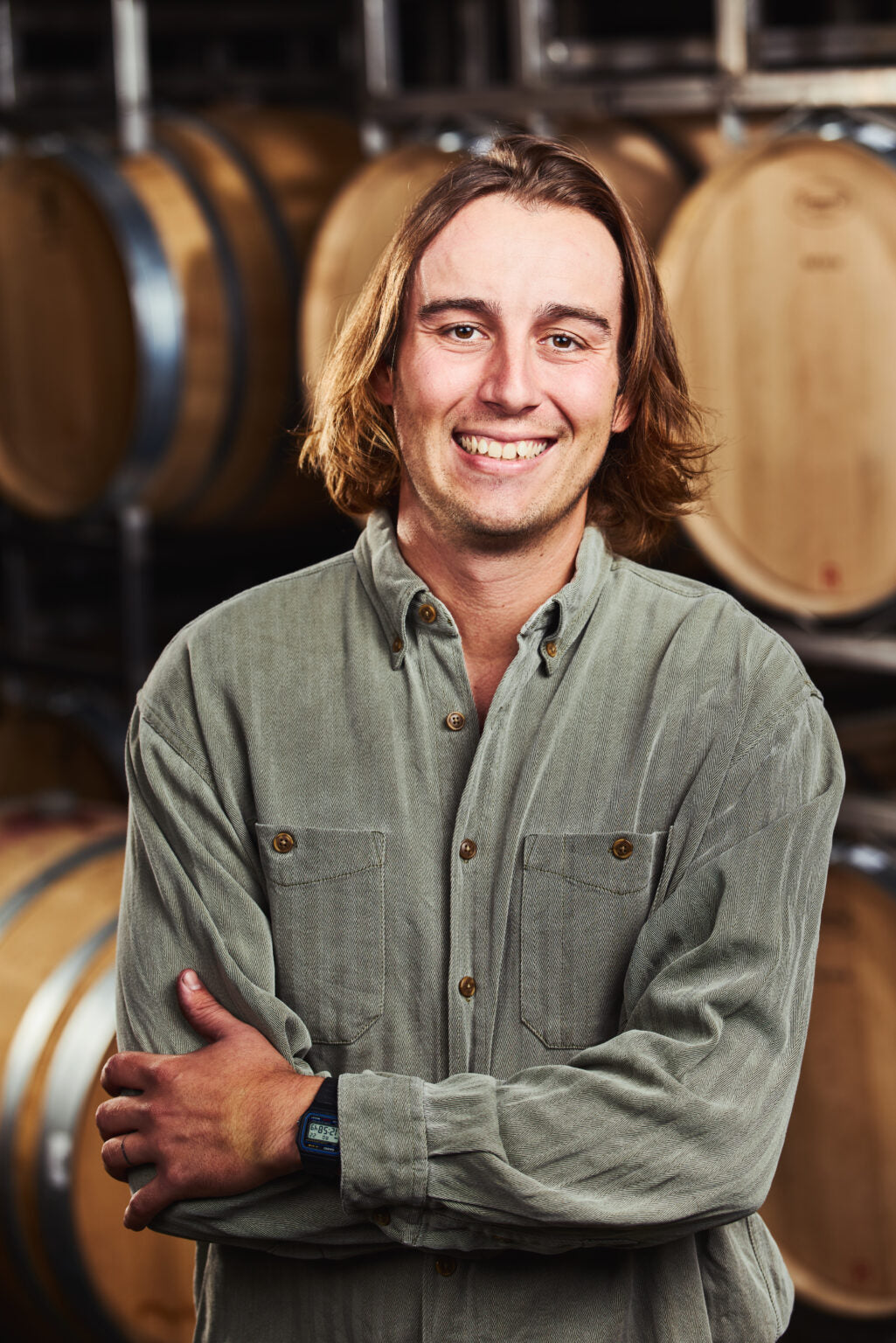 Taylor Bruchet, assistant winemaker headshot with wine barrels in the background
