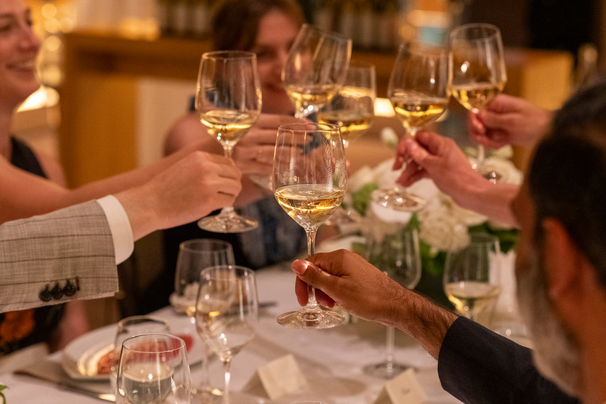 People raising glasses of white wine at a formal event