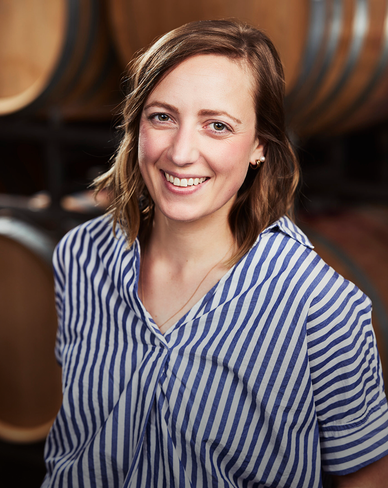 Megan Roberts Enologist headshot in front of wine barrels